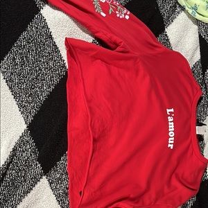 This is a long sleeve red crop top with floral designs on the sleeves